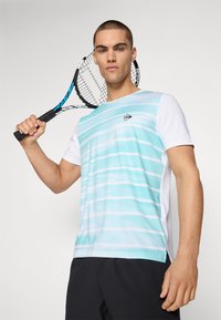 Helles blau-weiß gestreiftes Sport-T-Shirt mit Rundhalsausschnitt und Logodetail, kombiniert mit schwarzen Shorts und einem Tennisschläger.