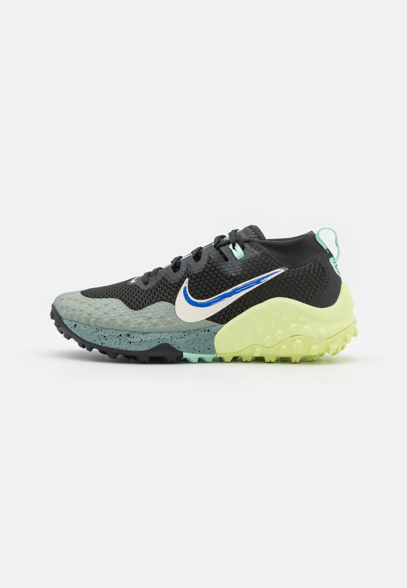 Czarno-zielony but sportowy z teksturowaną cholewką, białym logo Nike i masywną żółtą podeszwą. Posiada siateczkowy wzór oraz nakrapiane akcenty.