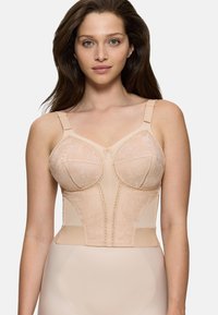 Donna con lunghi capelli castani che indossa un bustier di pizzo color nudo con spalline regolabili, su uno sfondo chiaro e uniforme.