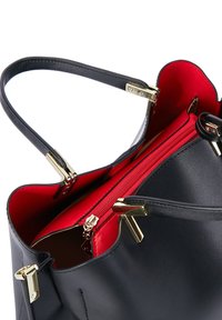 Marine lederen schoudertas met een helderrode binnenkant, gouden accenten en een ritscompartiment voor veilige opslag.