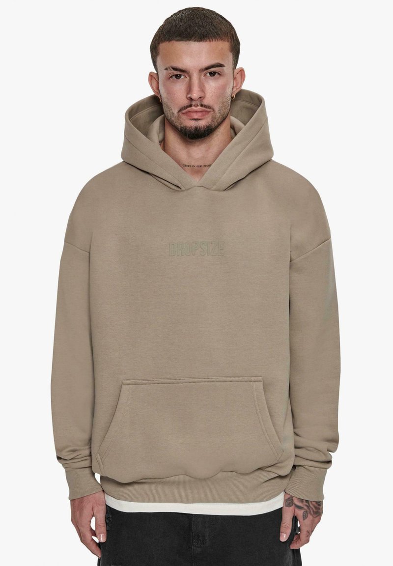 Beige hoodie lavet af blødt stof, med en frontlomme, justerbar hætte og præget "DROPSIZE" logo på brystet.
