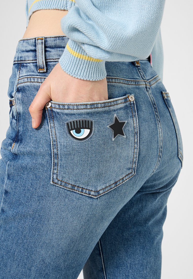 Denim jeans met een medium wassing, voorzien van twee decoratieve patches: een oog met wimpers en een zwarte ster op de rechter achterzak.