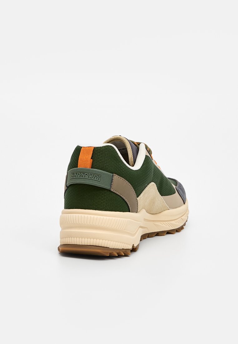 Zapatilla verde y beige con tejido texturizado, suela de goma, acento naranja y detalle con logo en el talón. Construcción de múltiples materiales.