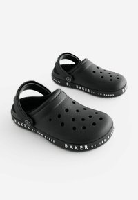 Črne klompke iz plastike z zračnimi odprtinami, mehkim notranjim delom in črnim trakom. Podplat ima bele napise "BAKER by TED BAKER."