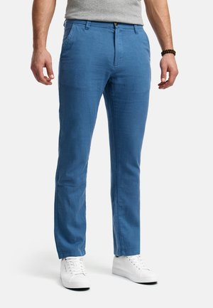 Pantalones de algodón azules con un diseño de pierna recta, que cuentan con un cierre de botón, bolsillos estándar y combinados con zapatillas blancas.