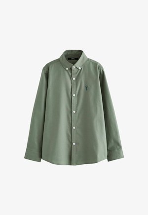 Zaļš pogājamais krekls, kas izgatavots no gludas kokvilnas. Iezīmes ietver apkakli, garas piedurknes un mazu zilu logotipu uz krūtīm. Priekšā ir baltas pogas.