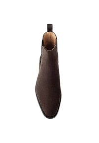 Bottine en daim marron avec un bout pointu, un design épuré et une languette à l'arrière. Doublure intérieure lisse et semelle en cuir.