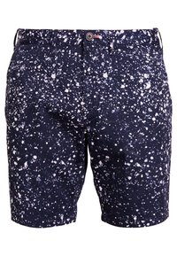 Granatowe szorty z wzorem w plamki w kolorze białym. Wykonane z tkaniny o gładkiej fakturze, wyposażone w zapięcie na guzik oraz kieszenie.