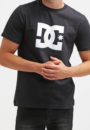 Czarny t-shirt z krótkim rękawem z dużym białym logo DC ozdobionym gwiazdką. Wykonany z gładkiego bawełnianego materiału, dopasowany fason.