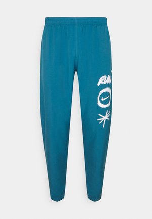 Türkisfarbene Jogginghosen mit elastischem Bund. Weiße Grafiken, darunter "RUN" und ein rundes Logo, auf dem rechten Bein. Leichter Stoff.