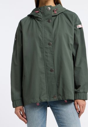 Veste à capuche vert foncé avec fermeture à boutons, poignets élastiques, cordons roses et petite poche zippée sur la manche gauche portée avec un jean bleu clair.