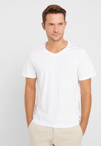 White V-neck t-shirt in cotton, short sleeves, relaxed fit. Soft texture, no visible patterns, plain design, suitable for casual wear.
