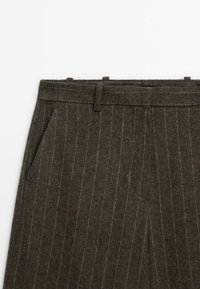 Pantalon en laine gris foncé à fines rayures, avec passants de ceinture et poches latérales, montré de la taille jusqu'au milieu de la cuisse.