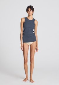 Sleeveless dark blue tank top featuring ribbed texture and fitted design, paired with nude underwear. Smooth fabric and minimalist style.