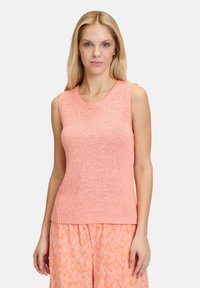 Mouwloos, koraalkleurig brei-top met een ronde halslijn, getextureerde weving en een getailleerde pasvorm, gecombineerd met gestreepte oranje onderkleding.
