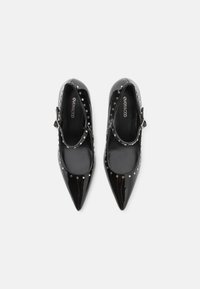 Zwarte gelakte leren schoenen met een spitse neus, enkelbandje en decoratieve zilveren studs rond de opening. Gladde textuur en strak ontwerp.