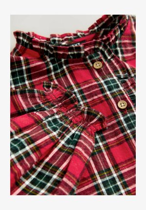 Rot-grün kariertes Hemd mit Rüschkragen, Holzknöpfen und gerafften Stoffdetails. Strukturierter Baumwollstoff.