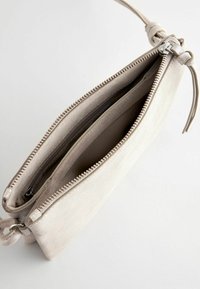 Jasnobeżowa zamszowa kopertówka z zamkiem błyskawicznym, posiadająca dwie komory, pleciony pasek oraz gładkie wykończenie wnętrza.