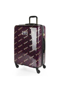 Maleta rígida en un brillante color púrpura con patrón del logo DKNY. Cuenta con un mango retráctil y cuatro ruedas negras para mayor movilidad.