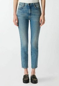 Jean en denim bleu clair avec une coupe ajustée, légère décoloration, design à cinq poches et fermeture à bouton à la taille. Longueur chevilles raccourcie.