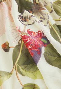 Kangas berflower dengan pola bunga yang cerah, menampilkan bunga merah dan ungu yang vibran, daun hijau besar, dan kupu-kupu yang halus di latar belakang krim lembut.
