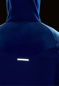 Felpa navy con una texture liscia e un design aderente; presenta una striscia riflettente sul retro per migliorare la visibilità in condizioni di scarsa illuminazione.