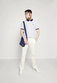 Λευκό πόλο μπλουζάκι με κόκκινο και μπλε γιακά, κρεμ παντελόνι και ναυτική τσάντα χιαστί. Υλικό από βαμβάκι, καλοκαιρινό σχέδιο και λευκά αθλητικά παπούτσια.