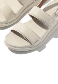 Beige synthetische sandalen met twee brede banden, een gladde textuur en een gevoerde zool. Lichtgewicht ontwerp, geschikt voor casual gebruik.