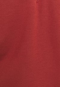 Tessuto di cotone rosso caratterizzato da una trama liscia e una distribuzione del colore uniforme, con una leggera lucentezza, adatto per abbigliamento o tessuti per la casa.