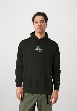 Sudadera negra con bolsillo canguro, presenta bordado del logo "New Era" en blanco y verde y puños elásticos, llevada sobre pantalones verdes.