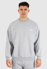 Sweatshirt gris en tissu en mélange de coton. Il poss�ède un col rond, des poignets côtelés et un petit logo en accent sur la poitrine.