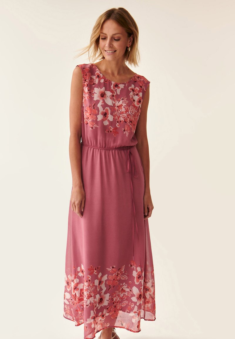 Maxi jurk van zacht roze stof, met een bloemenprint in oranjetinten en wit aan de onderkant, met een getailleerde taille en zonder mouwen.