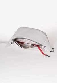 Borsa in pelle grigia con forma arrotondata, chiusura a zip, fodera interna rossa e finitura testurizzata. Presenta un cinturino da polso e hardware in metallo.