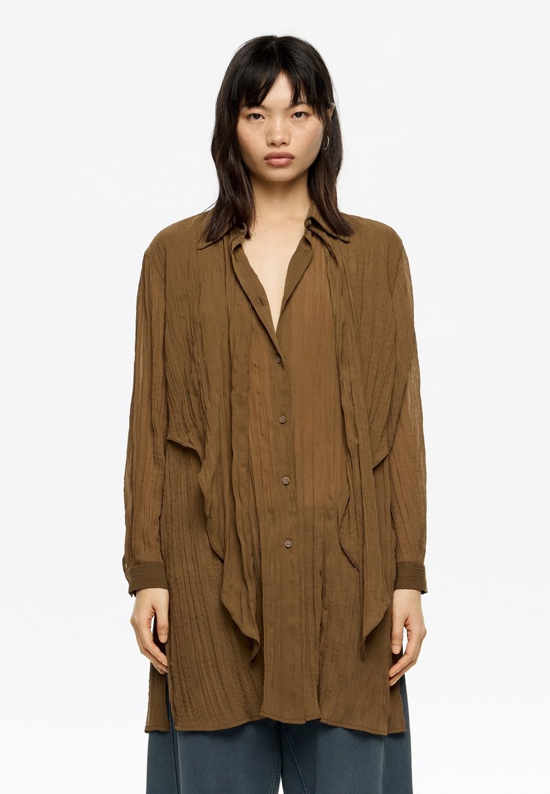 Brown textured button-up shirt with a draped design, long sleeves, and a collar. Slightly oversized with a relaxed fit.