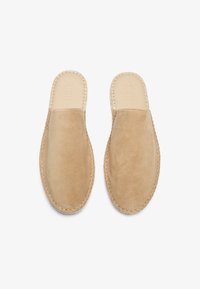 Lys beige mokkasiner i semsket skinn med en glatt overflate, med ton-i-ton sømmer og åpen bakdel for enkel påkledning. Flate såler gir komfort.
