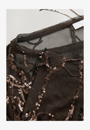 Läbipaistev must võrgusilmast topp, millel on keeruline pruunist sequins detail. Omab ümmargust kaelust ja õrnu rihmasid. Tekstureeritud, kihiline disain.