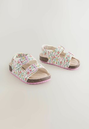 Sandales à motif floral avec brides roses ajustables, semelle intérieure en liège et semelle extérieure rose. Fond principalement blanc avec des accents colorés.