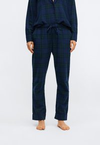 Marineblauw en groene geruite flanellen pyjama set met een knoopsluiting top en elastische taillebroek. Heeft een comfortabele pasvorm en een zachte textuur.