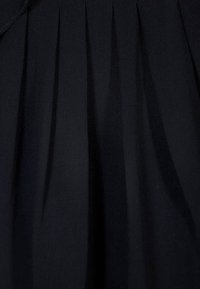 Svart plisserad tyg med slät textur, med vertikala veck. Enkel design utan synliga mönster eller detaljer.