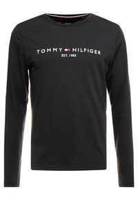 Schwarzes langärmliges T-Shirt aus Baumwolle mit Rundhalsausschnitt. Auf der Vorderseite steht "TOMMY HILFIGER" und "EST. 1985" in weißer Schrift.