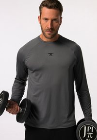 Graues langärmliges Trainingsshirt mit Rundhalsausschnitt, versehen mit einem dezenten Logo auf der Brust. Das Modell hält zwei schwarze Hanteln.