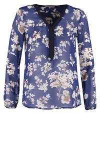 Blouse marine à manches longues, décolleté en V et bordures noires contrastantes. Présente un motif floral en crème et marron clair sur un tissu transparent.