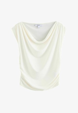 Hosszú, krémszínű, rövidujjú felső, puha és sima anyagból. Oldalt összegyűrve a laza illeszkedés érdekében.