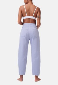 Lichtpaarse hoge taille jeans met een relaxed fit, twee achterzakken en een gladde denimtextuur. Witte banden van de bovenkant zijn zichtbaar.