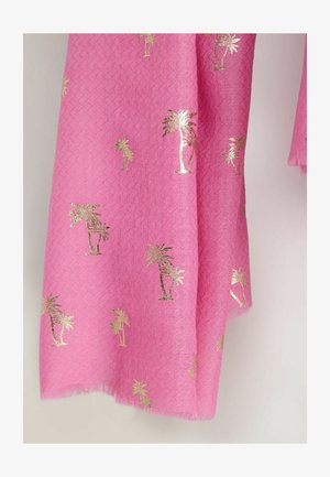 Svetlo roza tkanina z zlato kovinskimi vzorci palm, ki prikazuje teksturo in resice na robu, obešena na nevtralnem ozadju.