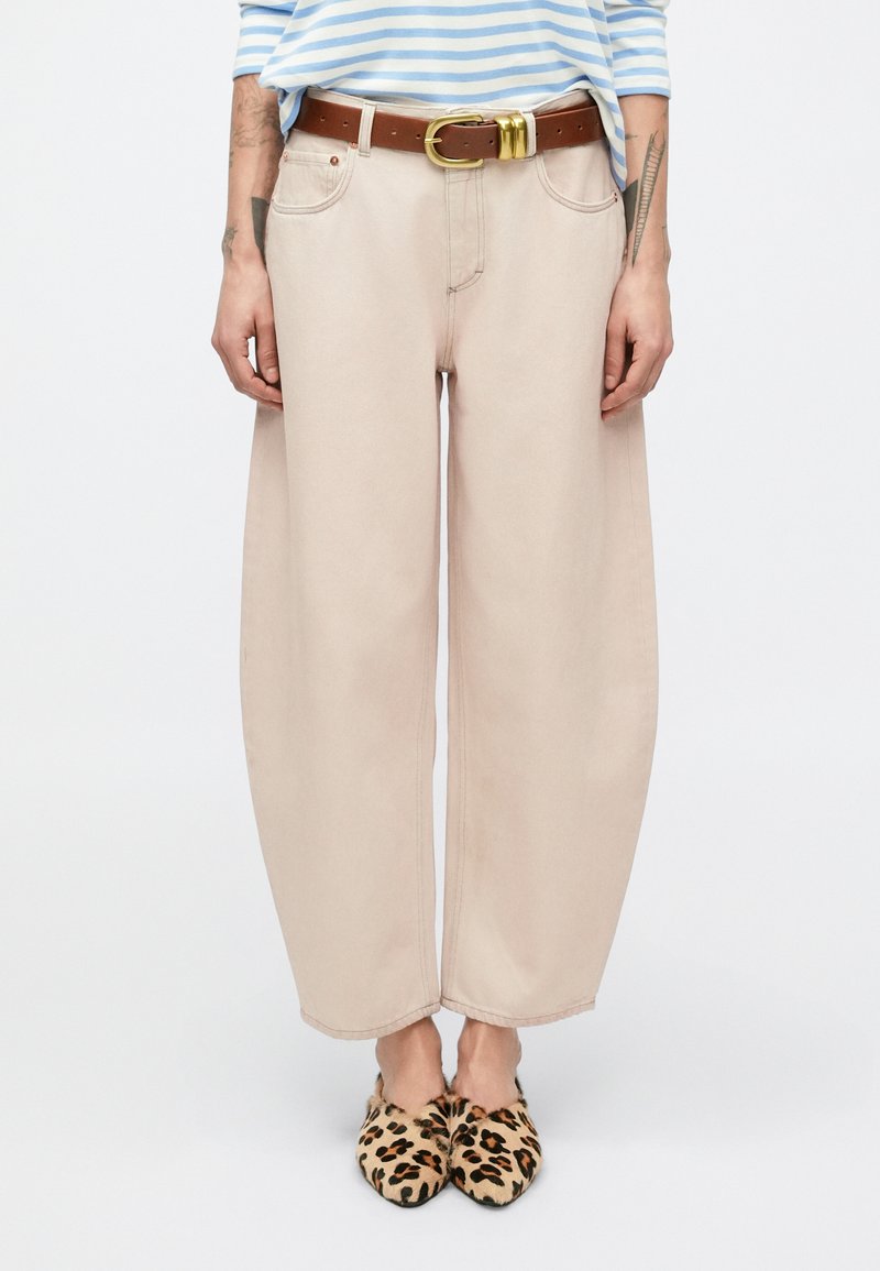 Μπεζ παντελόνι με φαρδιά πατζάκια και πλαϊνές τσέπες, σε συνδυασμό με καφέ ζώνη με χρυσή αγκράφα και mule με λεοπάρ σχέδιο. Λείο υφασμάτινο υλικό.