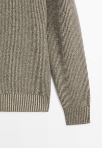 Pull à côtes dans des tons de vert terreux, présentant un corps texturé et des poignets rayés contrastants. Tissu doux avec une bande élastique à l'ourlet.