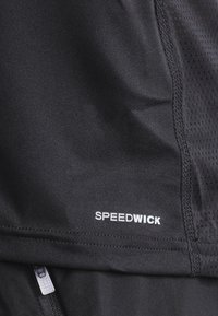 Mustat urheilukankaat, joissa on verkkokudontaa ja valkoinen "SPEEDWICK" -logo helman kohdalla, suunniteltu kosteuden hallintaan.