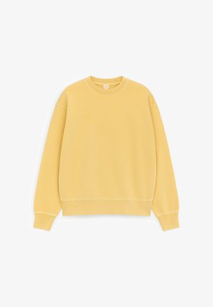 Solide pastelkleurige gele crewneck-trui met lange mouwen en geribbelde boorden en zoom, plat weergegeven op een witte achtergrond.
