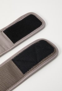 Grå stropper i stof med sorte velcro-patches, en med en glat overflade og den anden med et mesh-design. Synlige sømdetaljer.